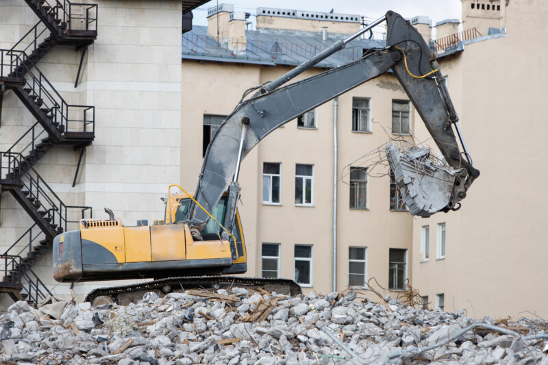 Building of the former hotel demolition for new construction, using a special hydraulic excavator-destroyer. Dismantling of house.